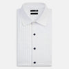 View 4 of product The Casino Royale White Dress Shirt in Cotton by Turnbull & Asser UK is a long-sleeve white dress shirt, crafted from crisp white cotton poplin with a pleated bib front, black buttons, and a classic collar, shown laid flat on a white background.