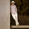 View 1 of product An older man in a light hat, Turnbull & Asser Beige Stripe Cotton Holiday Fit Shirt with Revere Collar & Single Button Cuff, and white pants leans casually against a tall concrete pillar outdoors, greenery blurred behind him.