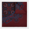 View 1 of product A red paisley silk pocket square from Turnbull & Asser UK features an intricate combination of floral and paisley patterns in rich shades of red, blue, and purple. Expertly folded to highlight both the detailed central design and distinctive border, this elegant accessory is finished with the “Turnbull & Asser” signature printed in the corner—making it a sophisticated addition to any formal outfit.