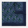 View 1 of product The Navy Blue Wave Silk Pocket Square by Turnbull & Asser UK showcases a playful motif of green and white fish swimming among wavy blue lines, with the brand’s name printed in white in the corner.