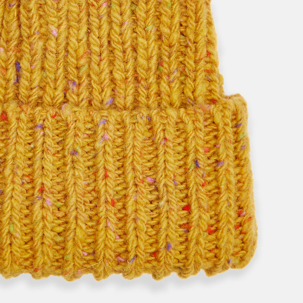 The Turnbull & Asser Yellow Donegal Ribbed Merino Hat features a mustard hue, folded brim, and subtle multicolored flecks in the yarn. Shown on a white background.