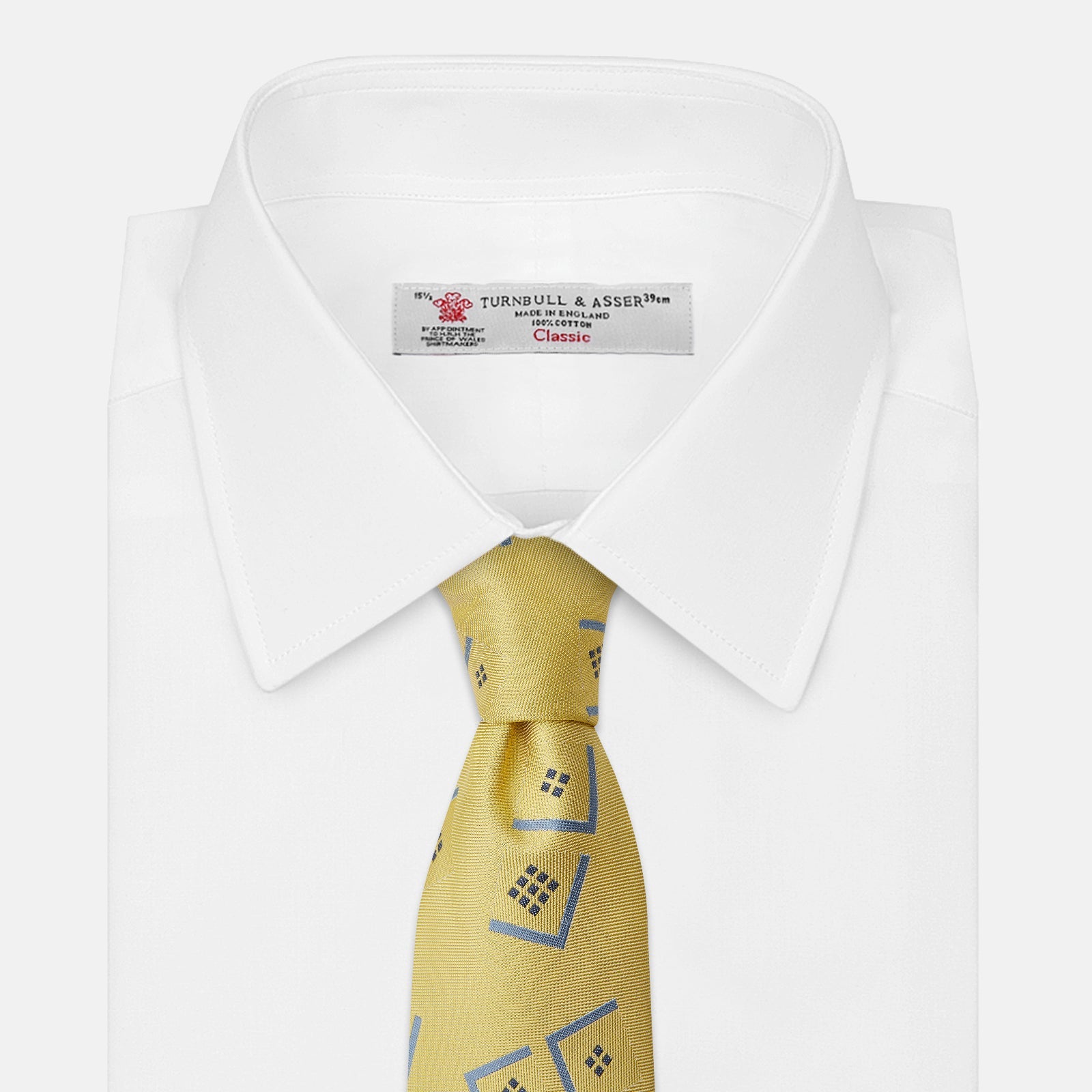 View 4 of product The Turnbull & Asser Yellow Graphic Deco Silk Tie features a subtle pattern of light blue geometric shapes and small black dots, elegantly rolled against a white background.