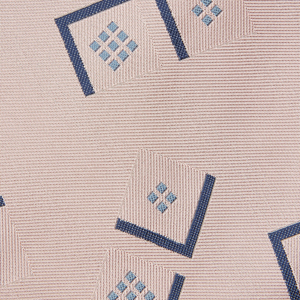 The Turnbull & Asser Pink Graphic Deco Silk Tie features blue geometric and square patterns on pale pink silk, shown rolled with the pointed end facing forward.