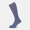 View 1 of product A single Powder Blue Mid-Length Merino Sock by Turnbull & Asser stands upright against a white background, showcasing its smooth texture and subtle vertical lines, with a length that reaches just below the knee.