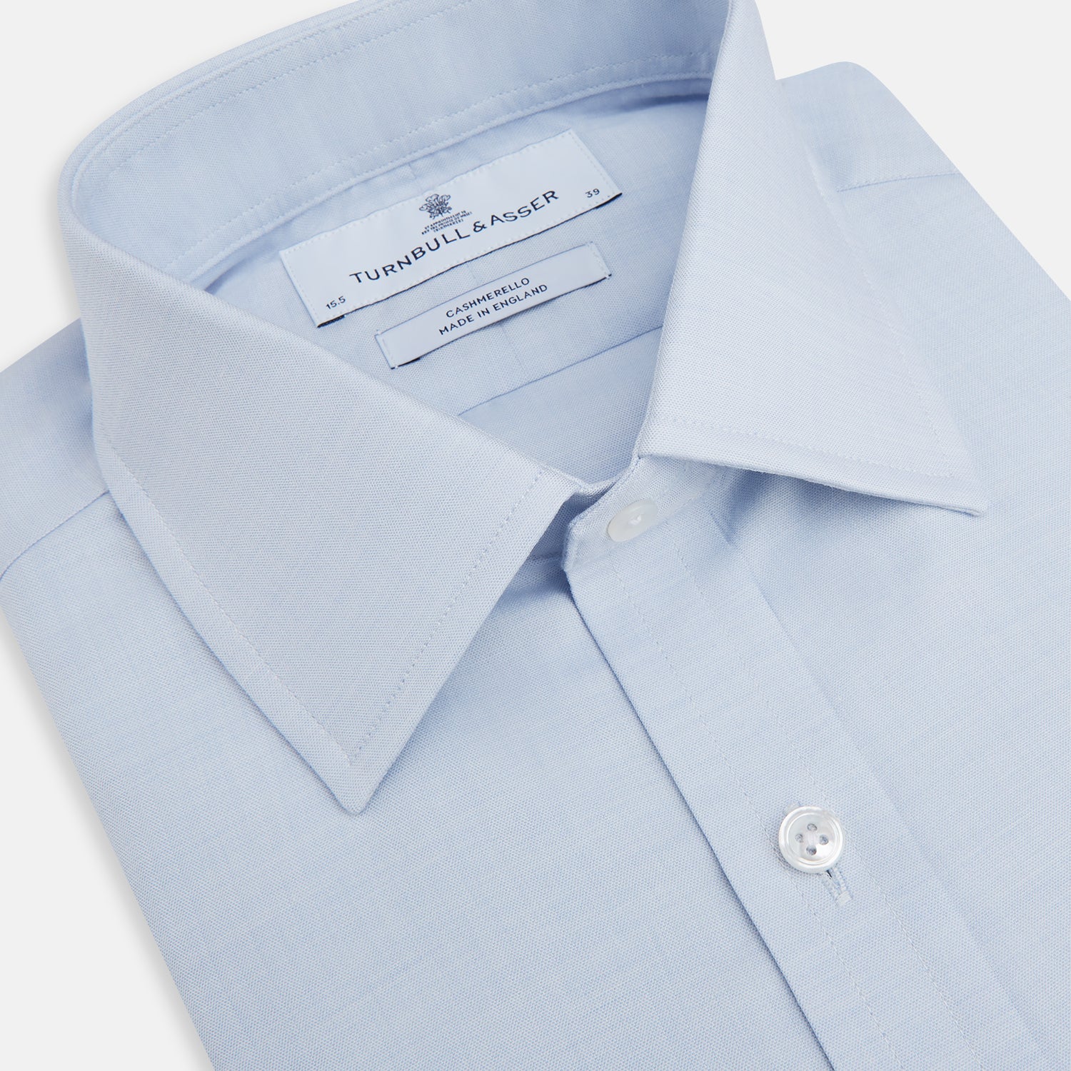 View 2 of product The Turnbull & Asser Blue Cashmerello Mayfair Shirt is a light blue cotton-cashmere blend with long sleeves, pointed collar, white buttons, and buttoned cuffs, shown on a plain white background.