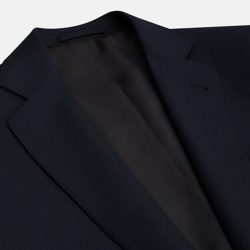 The Midnight Navy Wool Barrington Blazer by Turnbull & Asser features a single-breasted design with notched lapels, three front flap pockets, one chest pocket, and a two-button closure, neatly laid flat against a white background.