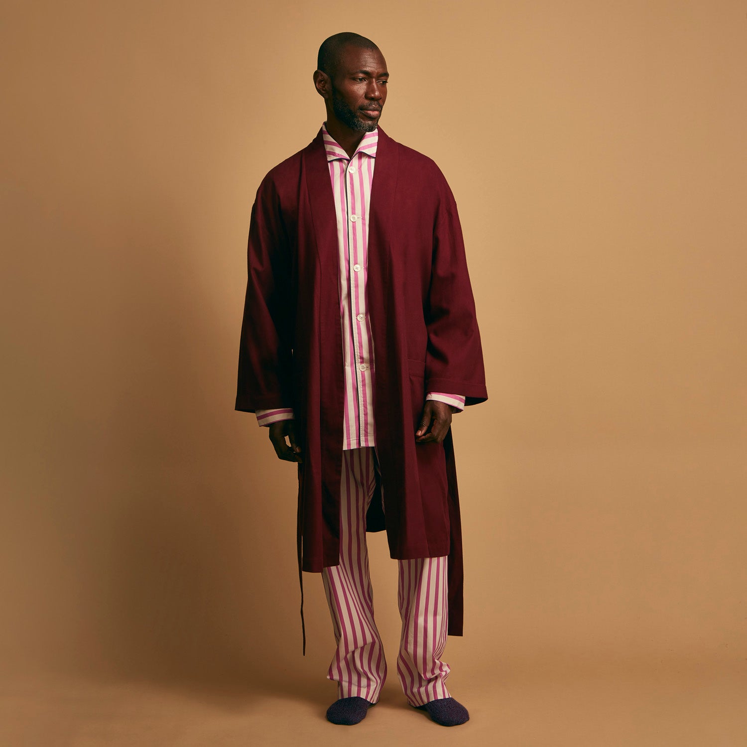 View 3 of product The Turnbull & Asser Pink Candy Stripe Cotton Traditional Pyjamas feature long sleeves, pants, vertical pink candy stripes, a camp collar shirt with buttons, chest pocket, and navy trim on the pocket and cuffs.