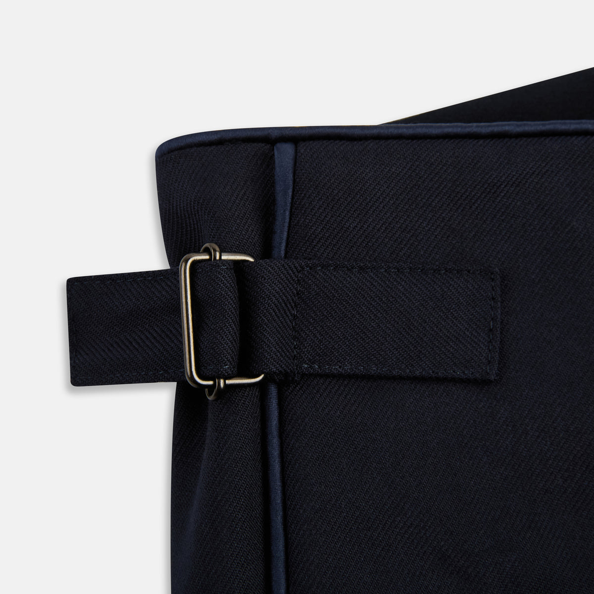View 6 of product The Casino Royale Midnight Blue Tuxedo Trousers in Wool by Turnbull & Asser UK are shown from the back, expertly crafted from virgin wool in a signature tuxedo style, featuring two buttoned back pockets and adjustable side tabs at the waistband.