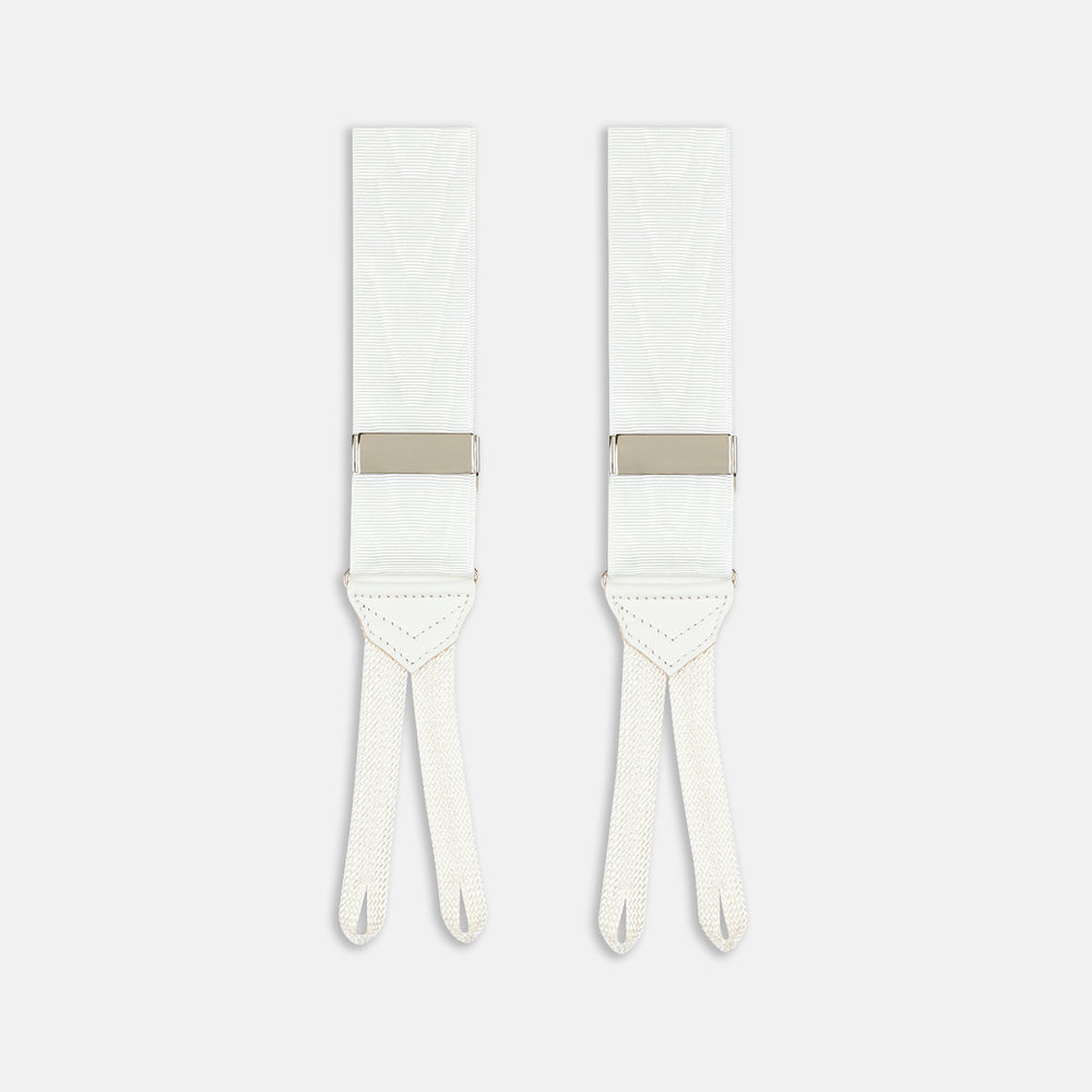 Two White Casino Royale Braces by Turnbull & Asser, as seen on James Bond, handmade in England with silver metal adjusters and leather detailing at the ends—displayed against a plain white background and offering the perfect finishing touch for a 007-inspired look.