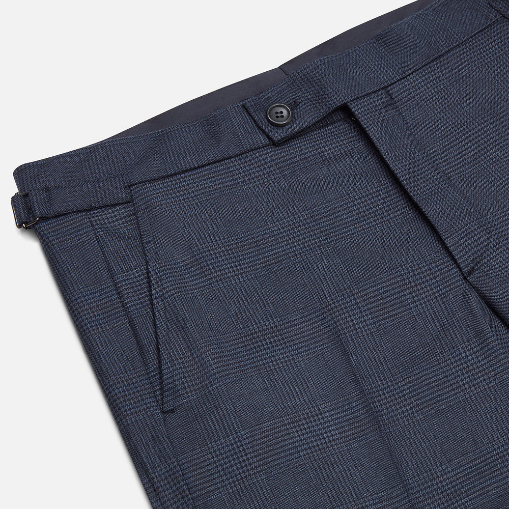 The Navy Check Henry Trousers by Turnbull & Asser are tailored-fit, dark blue pants with a subtle check pattern, front pockets, button closure, and belt loops, crafted from premium Italian wool and displayed on a plain white background.