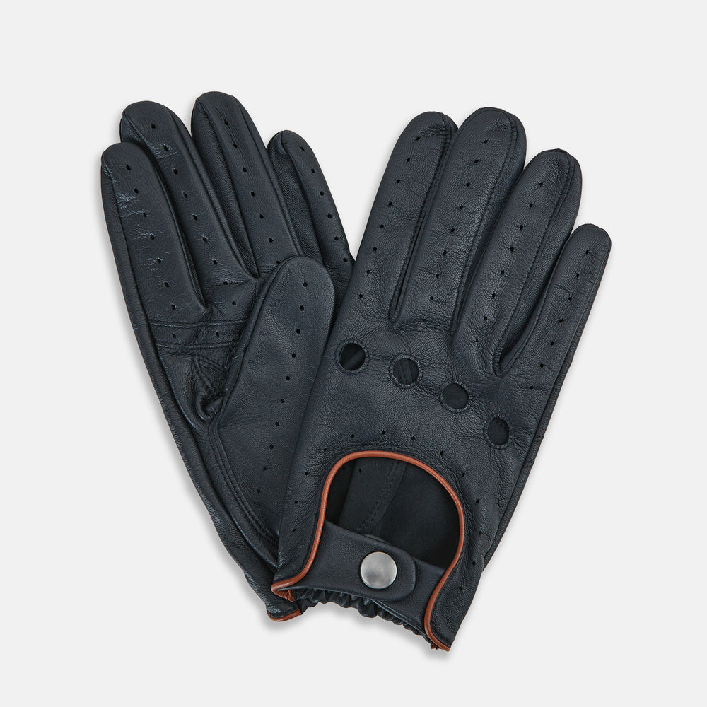 A pair of navy leather driving gloves from Turnbull & Asser UK, featuring perforations and snap closures; one glove displays the palm side while the other shows the back. These unlined Navy Driving Gloves combine style and flexibility for an optimal driving experience.