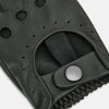 View 3 of product A pair of forest green leather unlined driving gloves from Turnbull & Asser UK, featuring perforated knuckles and backs, snap closures, and visible stitching, displayed flat on a white background. These gloves offer flexibility and comfort for an exceptional driving experience.