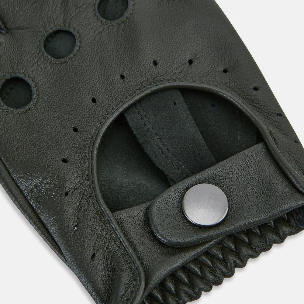 A pair of forest green leather unlined driving gloves from Turnbull & Asser UK, featuring perforated knuckles and backs, snap closures, and visible stitching, displayed flat on a white background. These gloves offer flexibility and comfort for an exceptional driving experience.