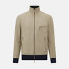 View 1 of product A Fairway Sand Golf Jacket in Linen by Turnbull & Asser UK, crafted from lightweight herringbone linen, features a front zipper, a chest zip pocket, two side zip pockets, and dark navy cuffs, collar lining, and waistband. Shown on a plain white background.