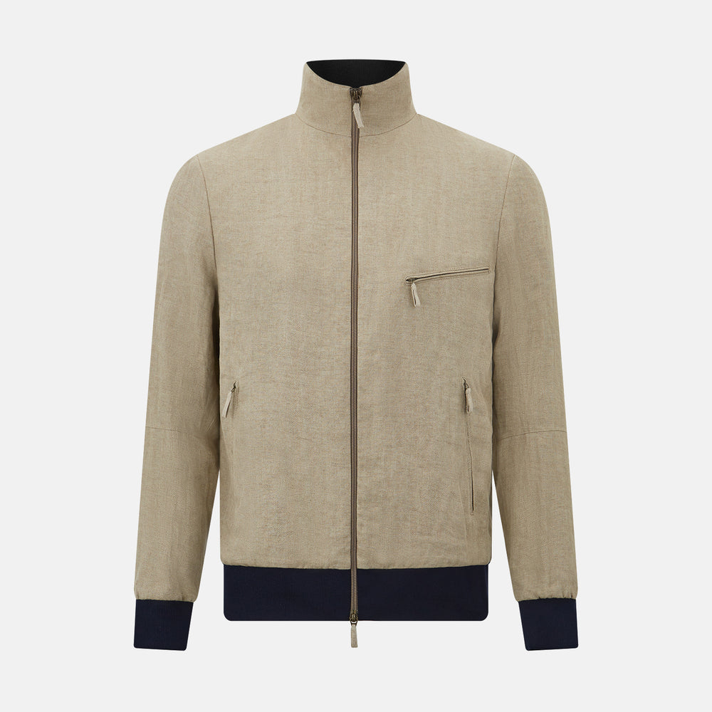 A Fairway Sand Golf Jacket in Linen by Turnbull & Asser UK, crafted from lightweight herringbone linen, features a front zipper, a chest zip pocket, two side zip pockets, and dark navy cuffs, collar lining, and waistband. Shown on a plain white background.