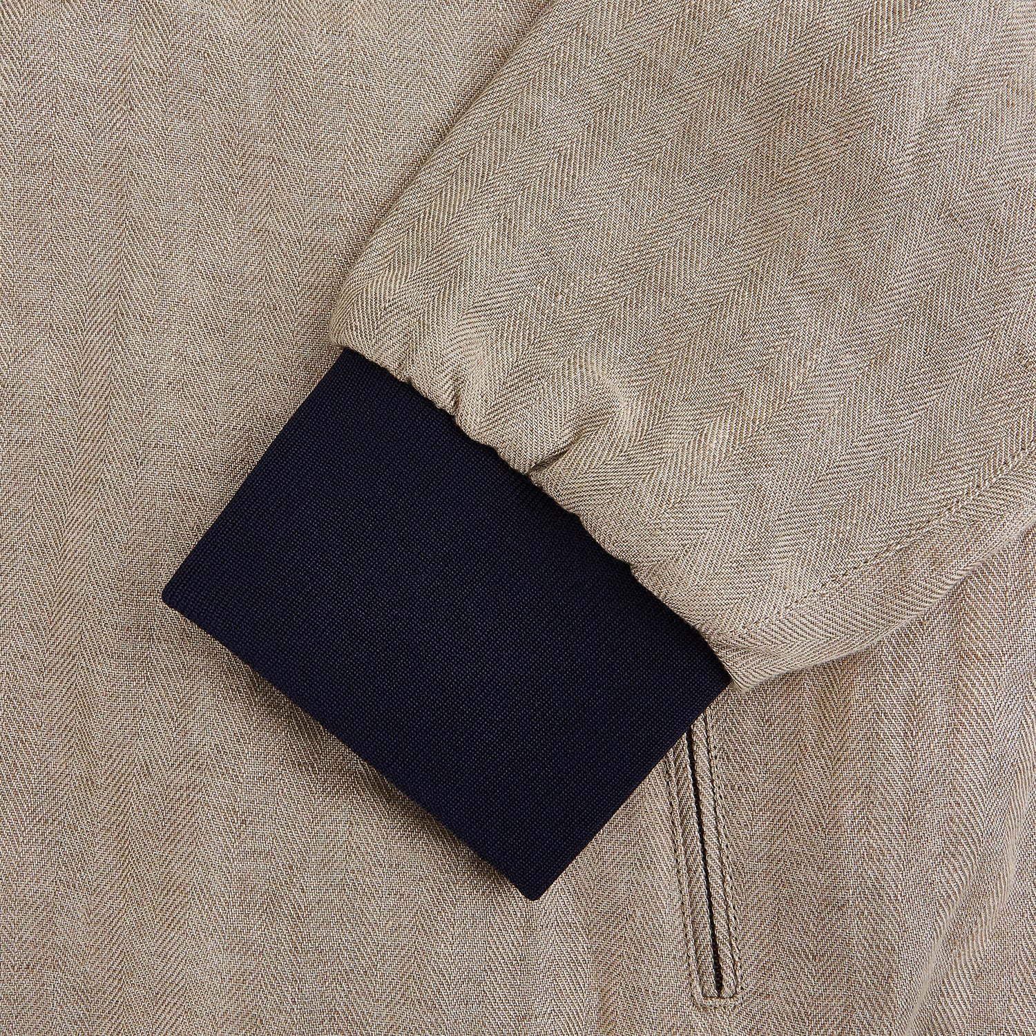 View 4 of product A Fairway Sand Golf Jacket in Linen by Turnbull & Asser UK, crafted from lightweight herringbone linen, features a front zipper, a chest zip pocket, two side zip pockets, and dark navy cuffs, collar lining, and waistband. Shown on a plain white background.