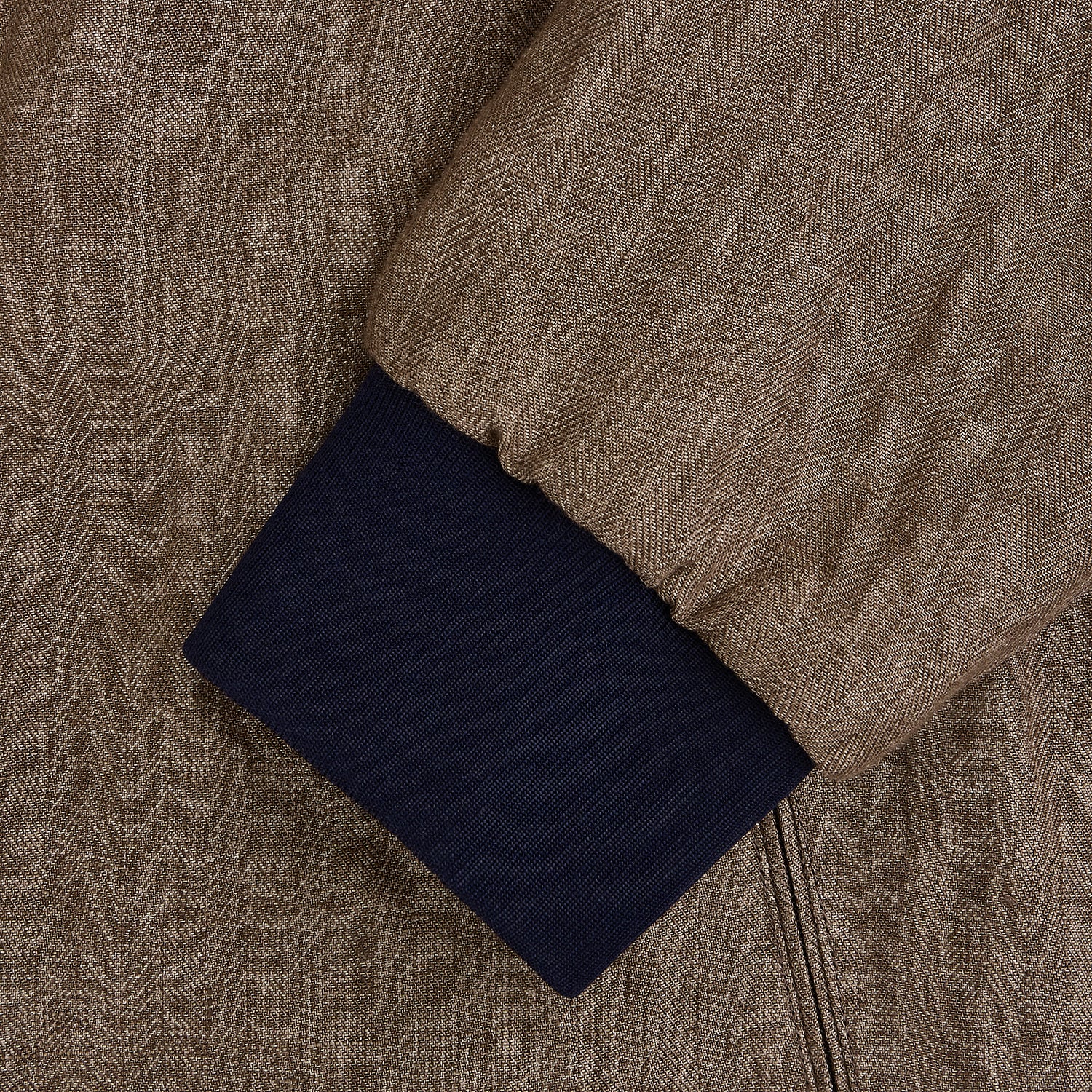 View 4 of product The Fairway Pinecone Golf Jacket in Linen by Turnbull & Asser UK is a brown zip-up jacket featuring a high collar, two side pockets, a zippered chest pocket, and dark cuffs and hem. Crafted from lightweight herringbone linen, it is displayed on a white background.