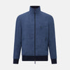 View 1 of product Introducing the Fairway Denim Golf Jacket in Linen by Turnbull & Asser UK—a blue zip-up jacket featuring a high collar, two side pockets, and a zippered chest pocket. The contrasting darker cuffs and hem accentuate its denim-like linen texture, making it the perfect versatile golf jacket for cooler days.