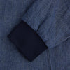 View 4 of product Introducing the Fairway Denim Golf Jacket in Linen by Turnbull & Asser UK—a blue zip-up jacket featuring a high collar, two side pockets, and a zippered chest pocket. The contrasting darker cuffs and hem accentuate its denim-like linen texture, making it the perfect versatile golf jacket for cooler days.