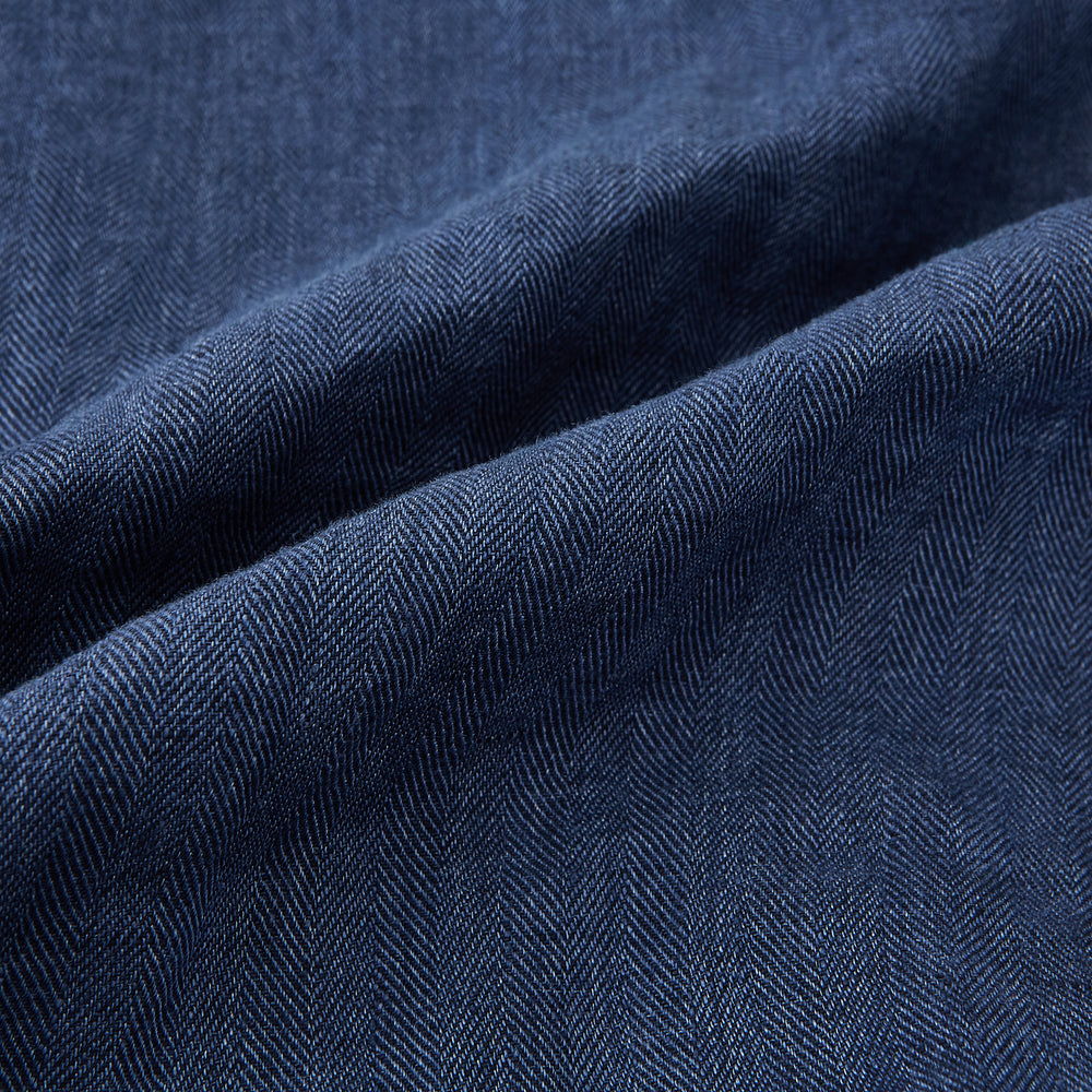 Introducing the Fairway Denim Golf Jacket in Linen by Turnbull & Asser UK—a blue zip-up jacket featuring a high collar, two side pockets, and a zippered chest pocket. The contrasting darker cuffs and hem accentuate its denim-like linen texture, making it the perfect versatile golf jacket for cooler days.