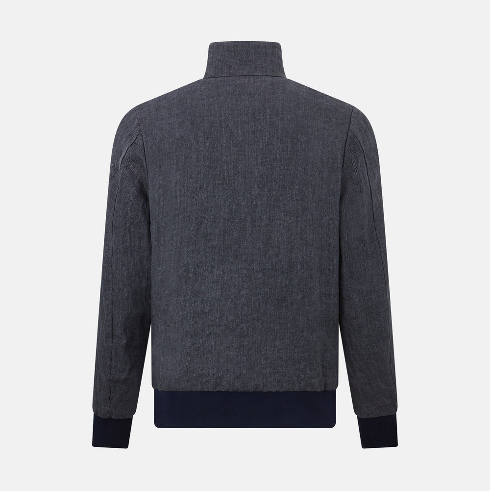 A front view of the Fairway Ash Golf Jacket in Linen by Turnbull & Asser UK is shown, featuring a high collar, two side zip pockets, a chest zip pocket, and black ribbed cuffs and hem. Crafted from lightweight gray herringbone linen for effortless warm-weather dressing, the jacket is displayed on a plain white background.
