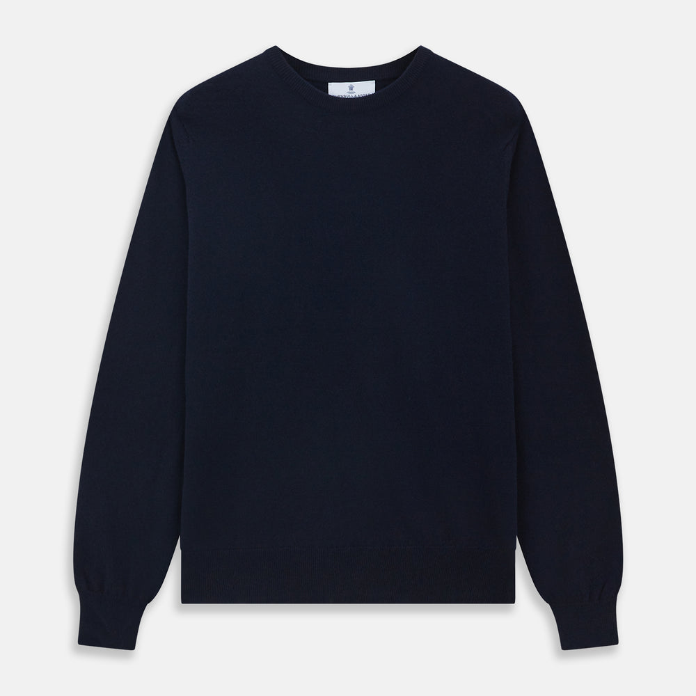 A luxurious navy crew neck cashmere jumper by Turnbull & Asser is laid flat on a white background, evoking timeless Scottish cashmere craftsmanship.