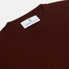 View 2 of product The Turnbull & Asser Port Cashmere Crew Neck Jumper, in dark brown, features a plain design with long sleeves and is shown laid flat on a white background.