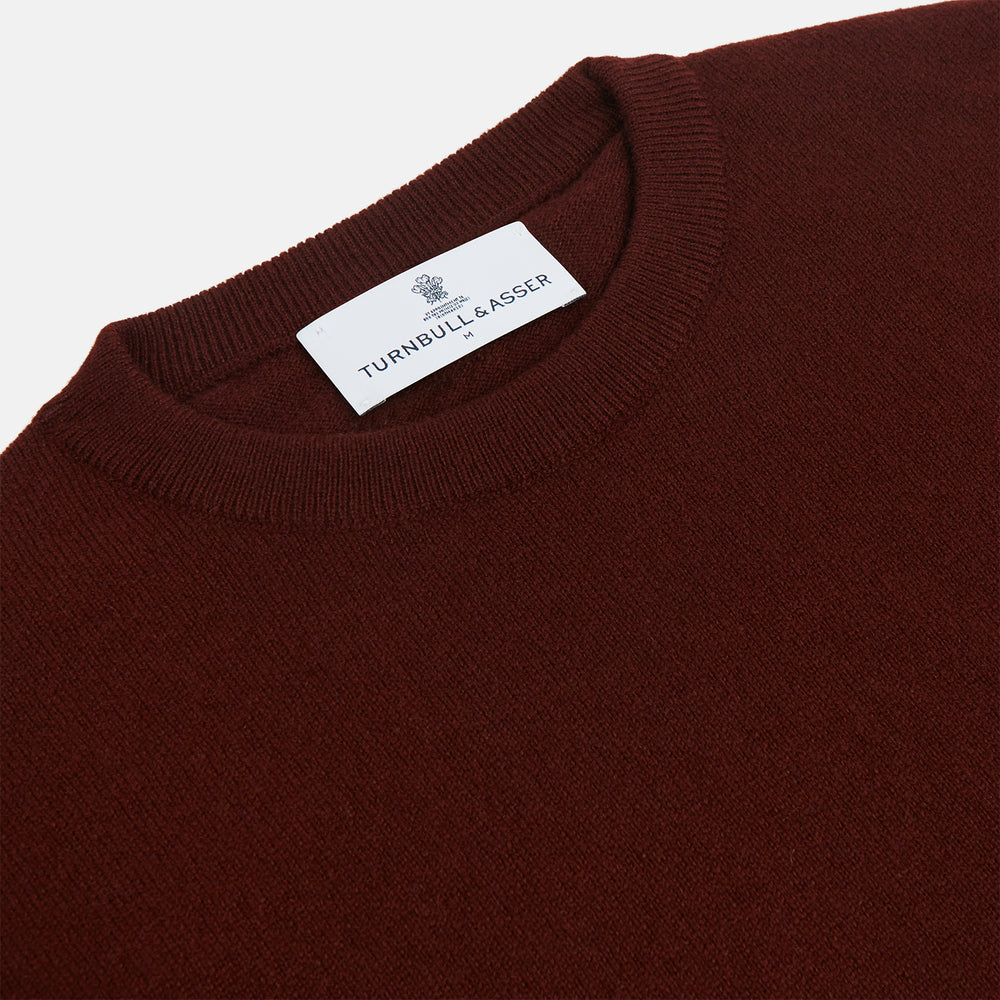 The Turnbull & Asser Port Cashmere Crew Neck Jumper, in dark brown, features a plain design with long sleeves and is shown laid flat on a white background.