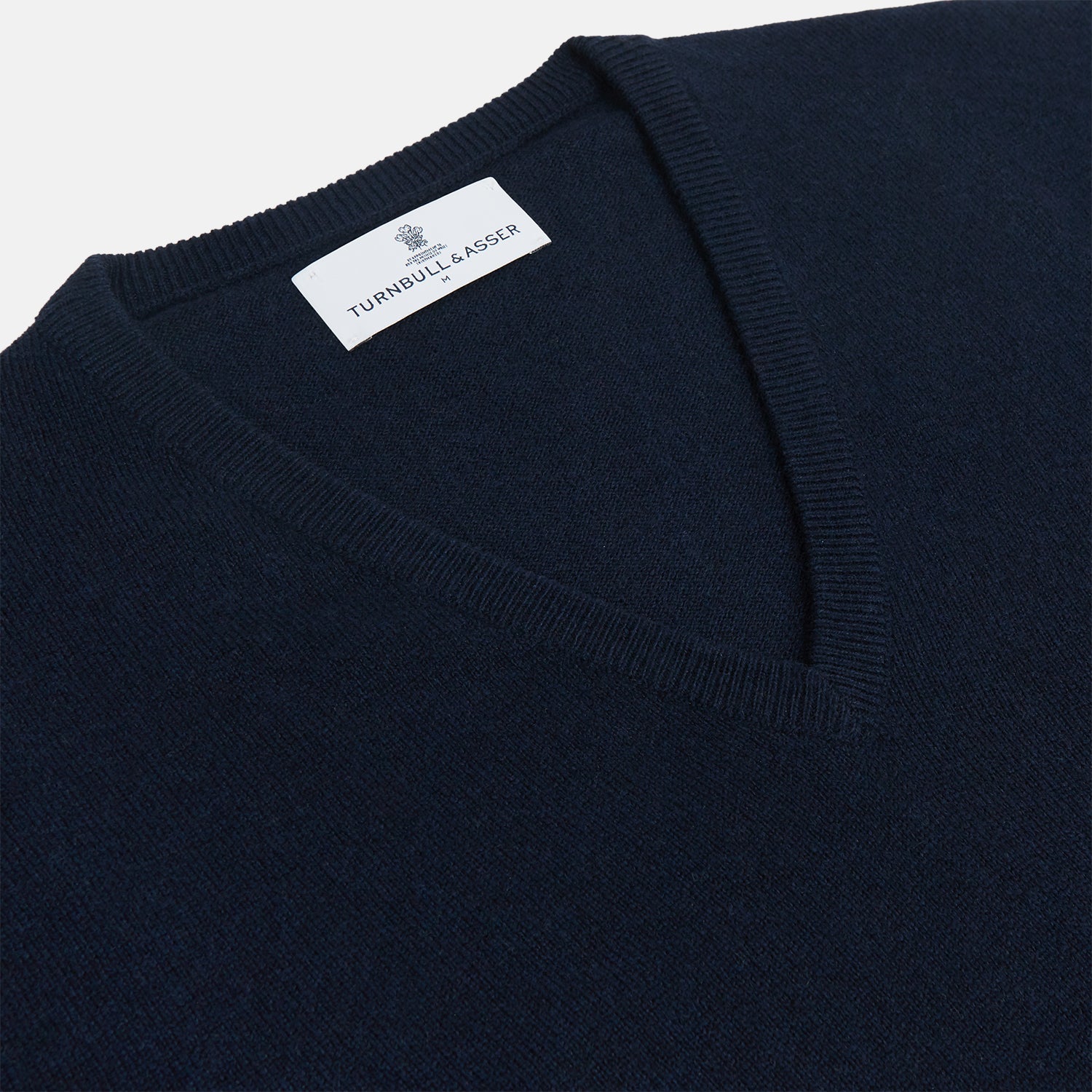 View 2 of product The Turnbull & Asser Navy V-Neck Cashmere Jumper, featuring long sleeves and ribbed cuffs and hem, is laid flat on a white background, showcasing its simple and classic design.