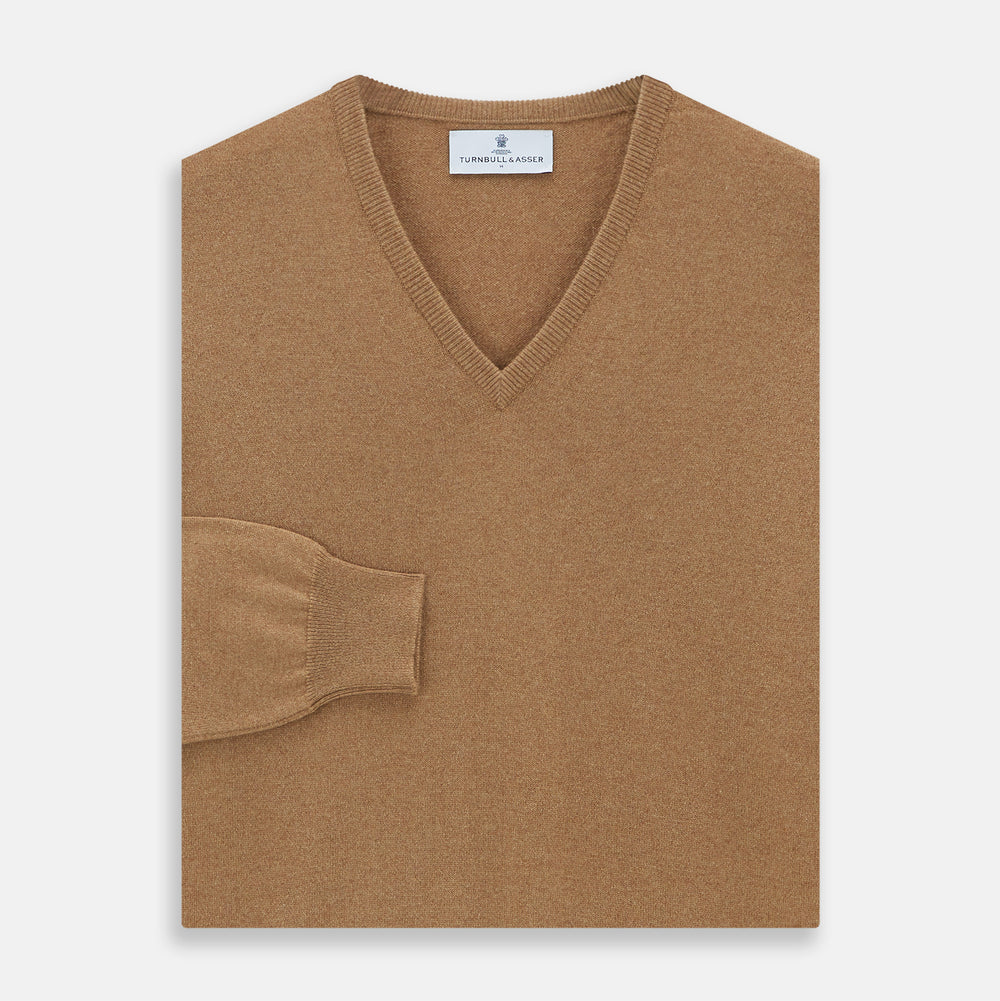 The Turnbull & Asser Natural V-Neck Cashmere Jumper, in camel, features long sleeves and ribbed cuffs, hem, and neckline. Crafted from Scottish cashmere, it’s laid flat on a white background for a refined smart casual look.