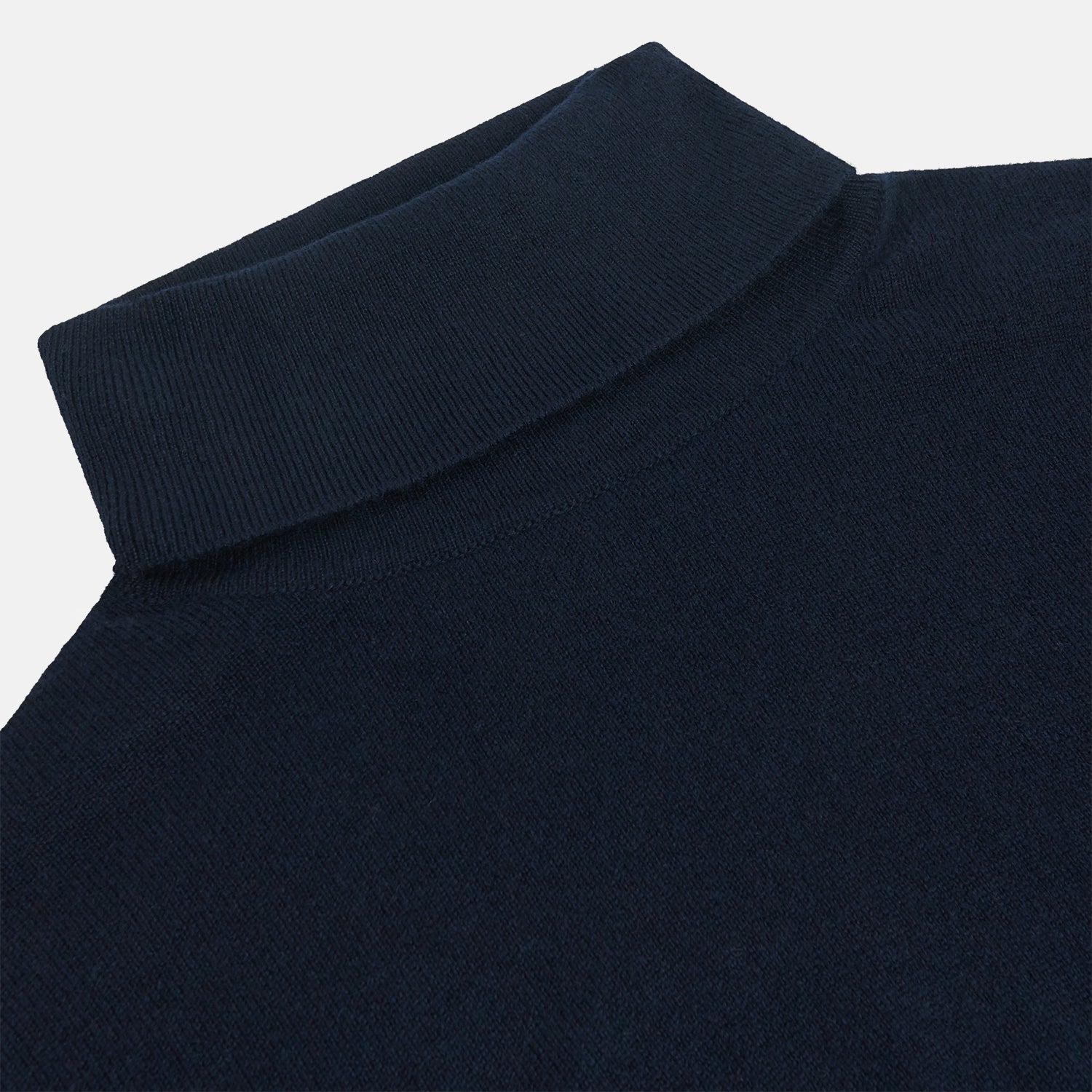 View 2 of product The Turnbull & Asser Navy Cashmere Roll Neck Jumper, with ribbed cuffs and hem, is a timeless autumn essential. Shown laid flat on a white background, this plain long-sleeved sweater offers classic style and comfort.