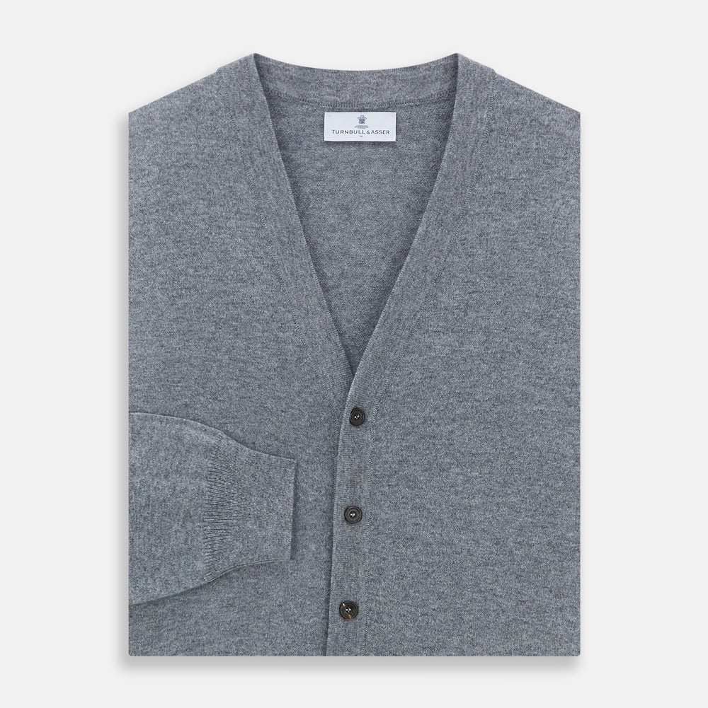 The Louis Flannel Grey Cashmere Cardigan by Turnbull & Asser features long sleeves, a V-neck, black front buttons, and two front pockets, making it ideal for transitional seasons. Shown laid flat on a white background.