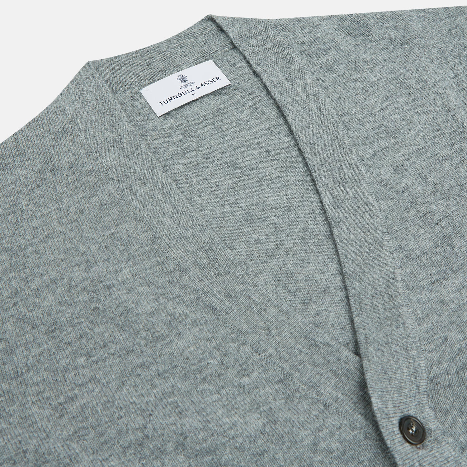 View 2 of product The Louis Flannel Grey Cashmere Cardigan by Turnbull & Asser features long sleeves, a V-neck, black front buttons, and two front pockets, making it ideal for transitional seasons. Shown laid flat on a white background.
