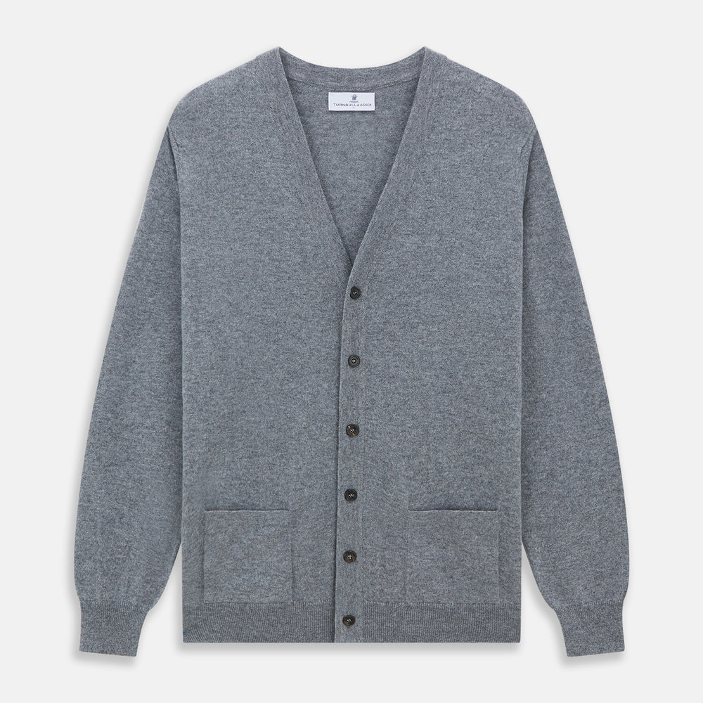 The Louis Flannel Grey Cashmere Cardigan by Turnbull & Asser features long sleeves, a V-neck, black front buttons, and two front pockets, making it ideal for transitional seasons. Shown laid flat on a white background.