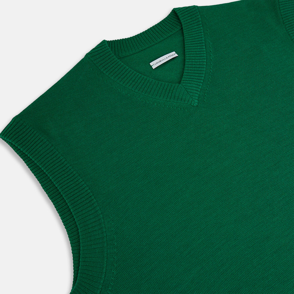 The Turnbull & Asser Hunter Green Fine Merino V-Neck Vest features a sleeveless design with ribbed edges, making it a stylish sweater vest for any gentleman. Shown against a plain white background.
