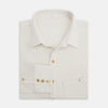 View 5 of product The Turnbull & Asser White Pique Shirt is a long-sleeve, white button-up with a chest pocket and beige buttons, laid flat on a white background, featuring an elevated silhouette inspired by elegant polos.