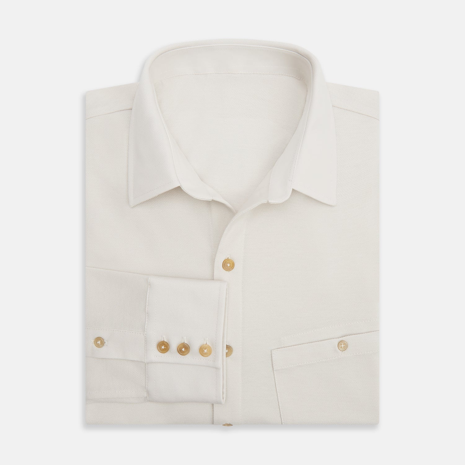 View 5 of product The Turnbull & Asser White Pique Shirt is a long-sleeve, white button-up with a chest pocket and beige buttons, laid flat on a white background, featuring an elevated silhouette inspired by elegant polos.