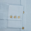 View 4 of product The Turnbull & Asser Pale Blue Pique Shirt is a long-sleeve button-up with an open collar, single chest pocket, and beige buttons, shown against a white background.