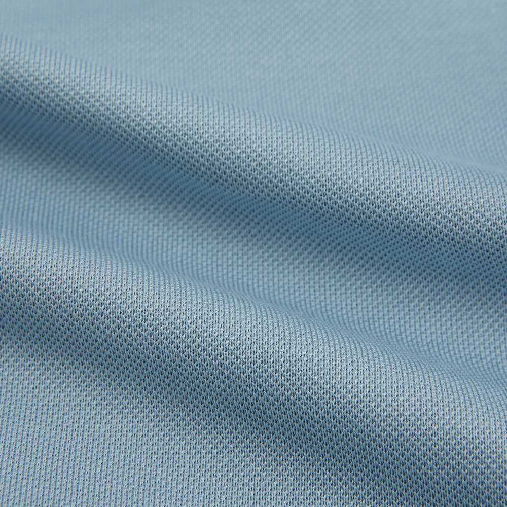 The Turnbull & Asser Pale Blue Pique Shirt is a long-sleeve button-up with an open collar, single chest pocket, and beige buttons, shown against a white background.