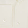 View 4 of product The Cream Nightshirt by Turnbull & Asser is a long-sleeved, cream-colored shirt dress with a collar, partial button front, chest pocket, and relaxed fit—ideal as comfortable sleepwear—shown on a plain white background.