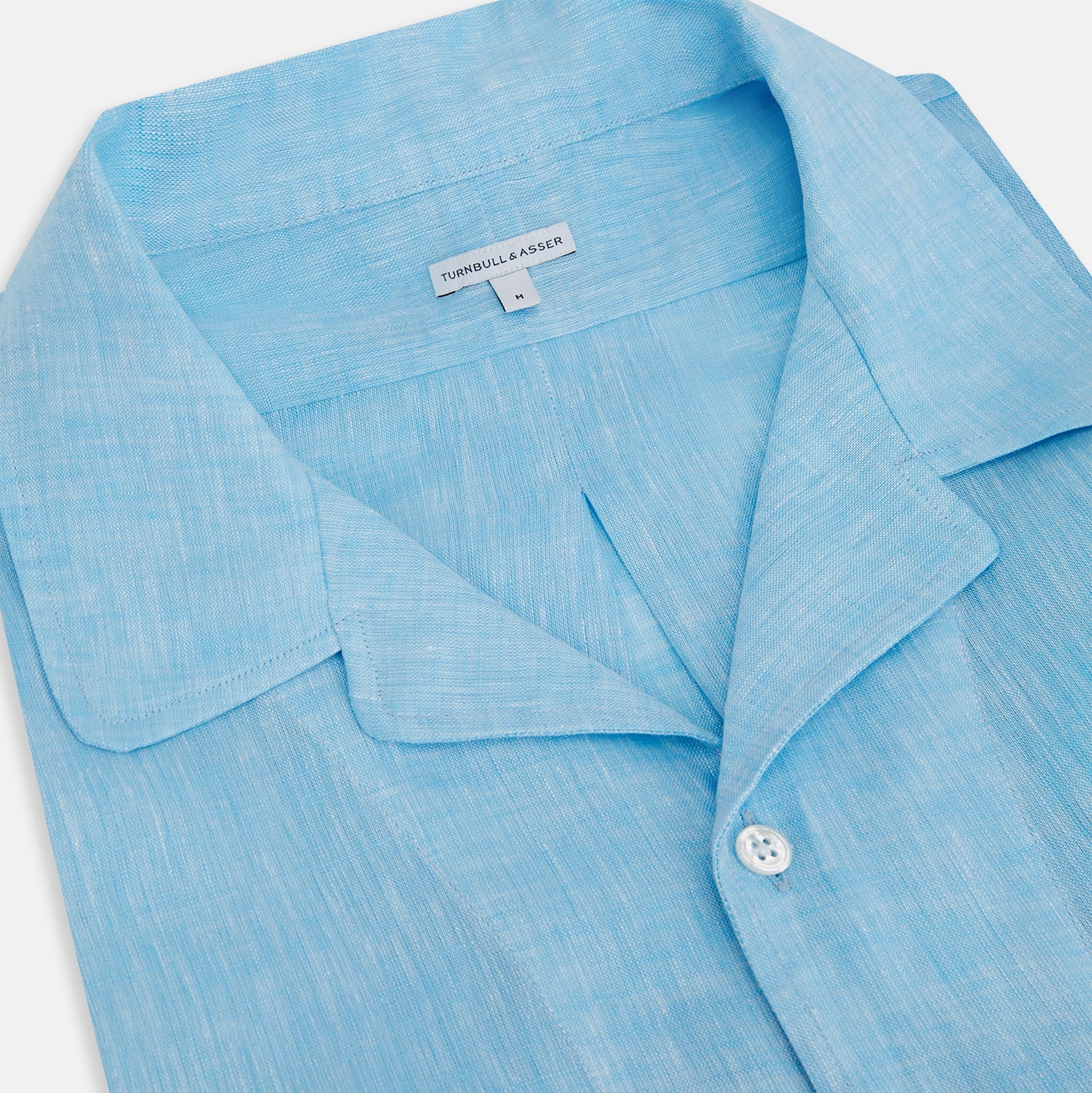 View 2 of product The QUARZO NIGHTSHIRT TURQUOISE LINEN by Turnbull & Asser is a relaxed-fit, long-sleeve collared nightshirt in soft turquoise linen, featuring a chest pocket and button placket, shown laid flat on a white background.