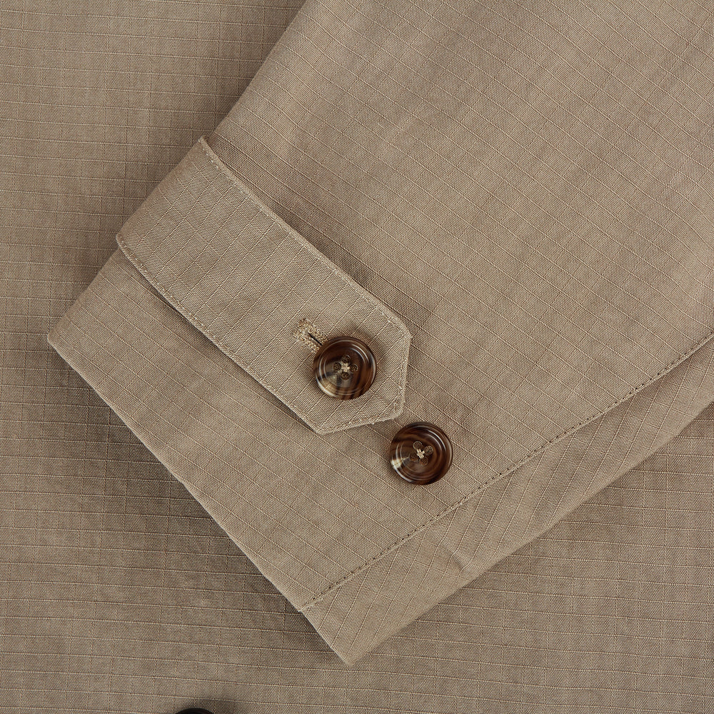 The Sand Long Albert Trench Coat by Turnbull & Asser UK features a double-breasted design, dark buttons, notched collar, and two slanted front pockets, offering timeless British style. Shown against a plain white background.