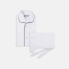 View 1 of product The Turnbull & Asser White Piped Cotton Pyjama Set, made from Egyptian cotton and featuring black piping and two buttons, is shown folded with a matching white tie-strap face mask on a light gray background.