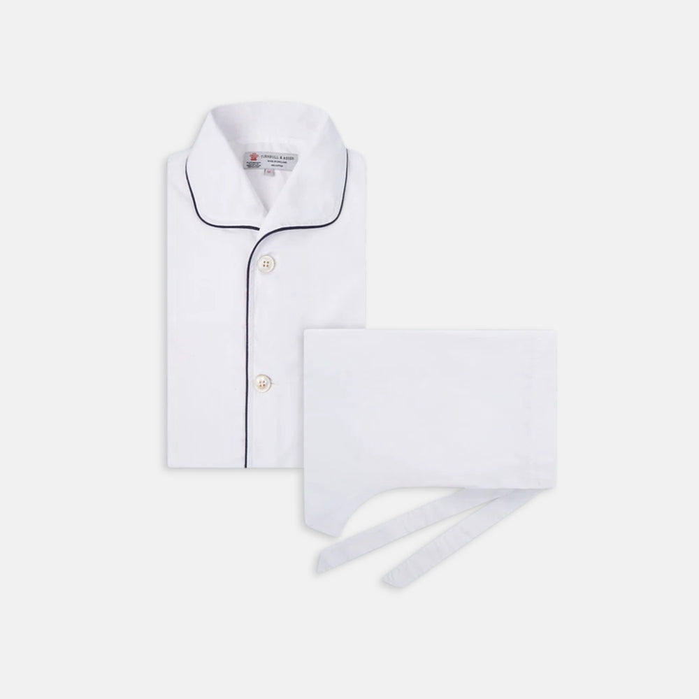 The Turnbull & Asser White Piped Cotton Pyjama Set, made from Egyptian cotton and featuring black piping and two buttons, is shown folded with a matching white tie-strap face mask on a light gray background.