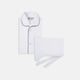 The Turnbull & Asser White Piped Cotton Pyjama Set, made from Egyptian cotton and featuring black piping and two buttons, is shown folded with a matching white tie-strap face mask on a light gray background.