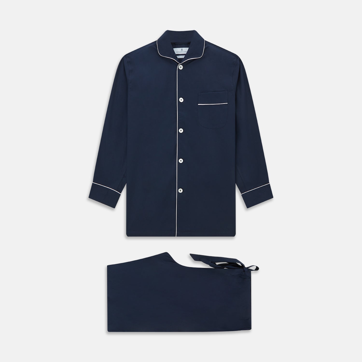 View 1 of product The Turnbull & Asser Navy Piped Cotton Pyjama Set features a navy blue long-sleeve top with white piping, front buttons, a chest pocket, and matching drawstring pants, all displayed on a white background.