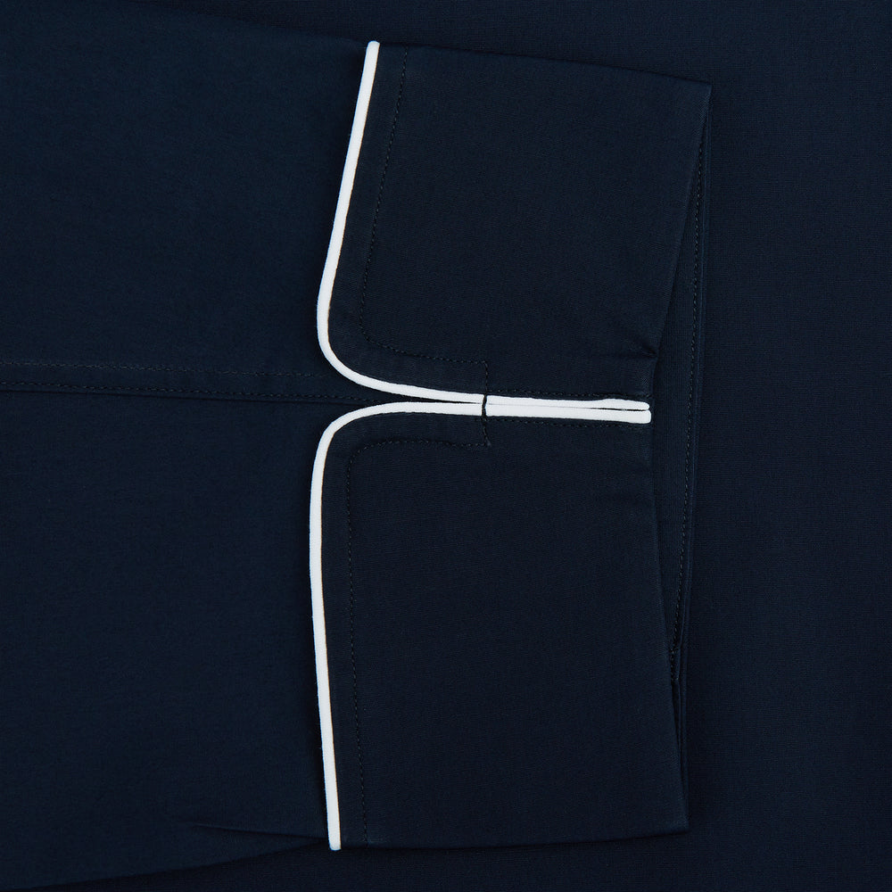 The Turnbull & Asser Navy Piped Cotton Pyjama Set features a navy blue long-sleeve top with white piping, front buttons, a chest pocket, and matching drawstring pants, all displayed on a white background.