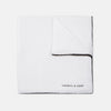 View 1 of product The Turnbull & Asser White and Black Piped Silk Pocket Square features a crisp white base with black edging, neatly folded to showcase the logo in black on the lower right—elegant monochrome style for any occasion, shown on a light gray background.