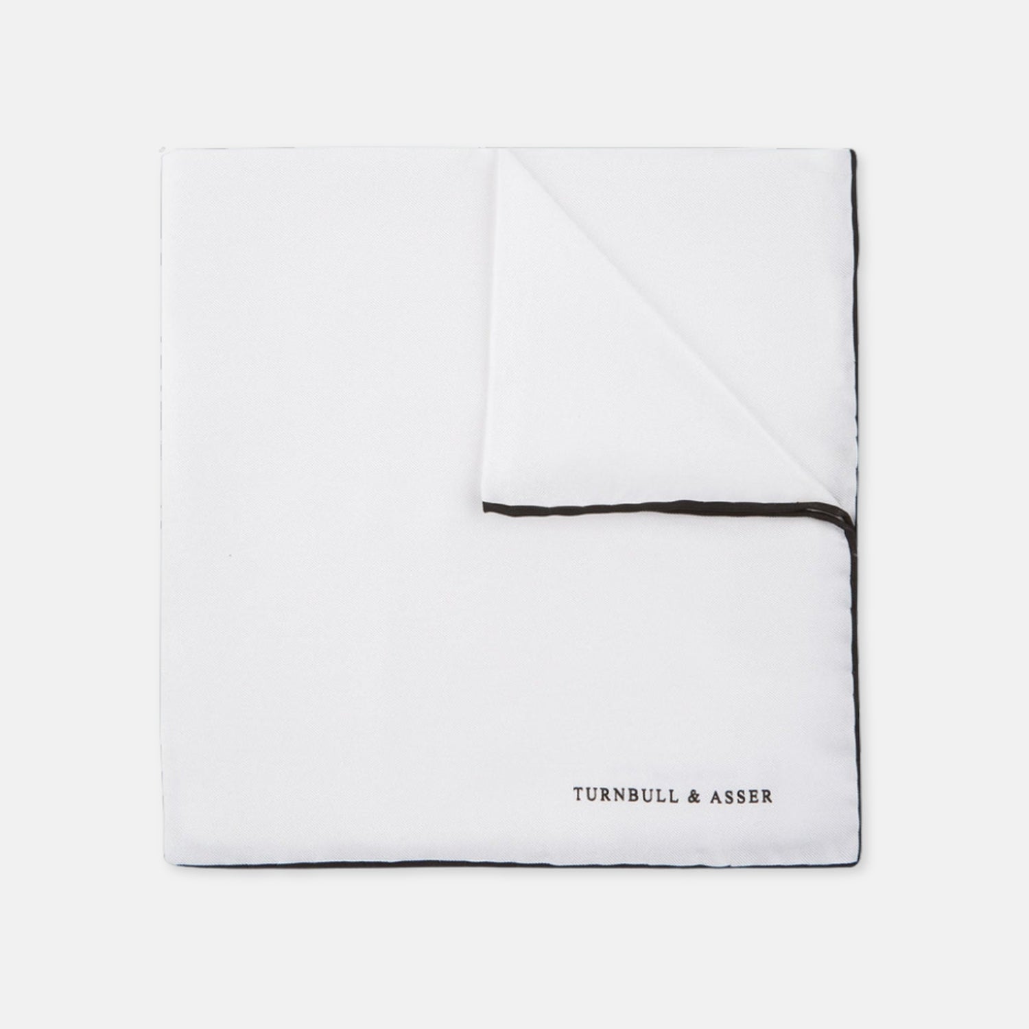 View 1 of product The Turnbull & Asser White and Black Piped Silk Pocket Square features a crisp white base with black edging, neatly folded to showcase the logo in black on the lower right—elegant monochrome style for any occasion, shown on a light gray background.