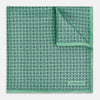 View 1 of product Floral Green Pocket Square in Silk by Turnbull & Asser UK, showcasing navy-blue floral geometric motifs on a bright green background. One corner is neatly folded to display both sides of the silk fabric, with "Turnbull & Asser UK" printed in the lower right corner.